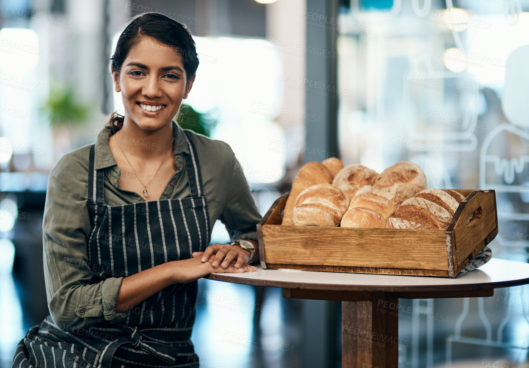 Buy stock photo Portrait of a female restaurant waiter, baker or coffee shop retail manager with fresh bread for breakfast. Smiling, happy and young woman bakery worker ready to welcome a customer and work in a cafe