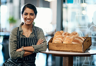 Buy stock photo Shot of a young woman serving a selection of freshly baked breads in her bakery