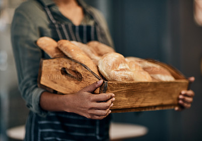 Buy stock photo Cropped shot of a woman holding a selection of freshly baked breads in her bakery