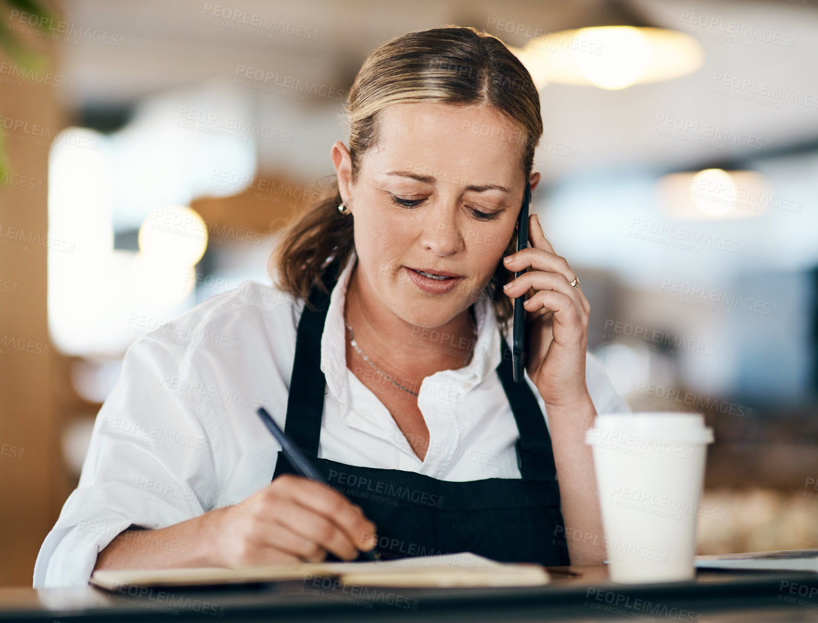 Buy stock photo Person, coffee shop or owner with phone call, notebook, or laptop for order confirmation. Thinking, writing and cafe woman on mobile technology for menu information, event planning and sales