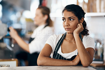 Buy stock photo Shot of a young woman looking unhappy while working behind the counter of a cafe