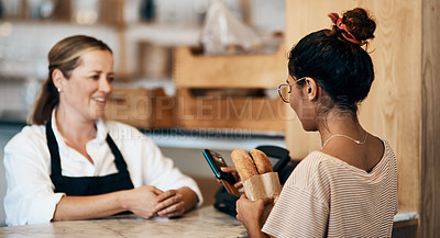 Buy stock photo Shot of a young woman paying with for freshly made baguettes at a bakery