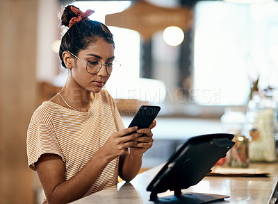 Buy stock photo Shot of a young woman paying with her smartphone in a cafe