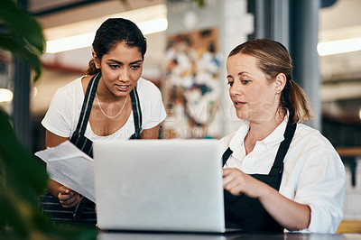 Buy stock photo Shot of two women using a laptop together while working in a cafe