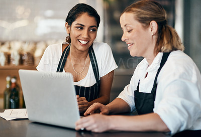 Buy stock photo Shot of two women using a laptop together while working in a cafe