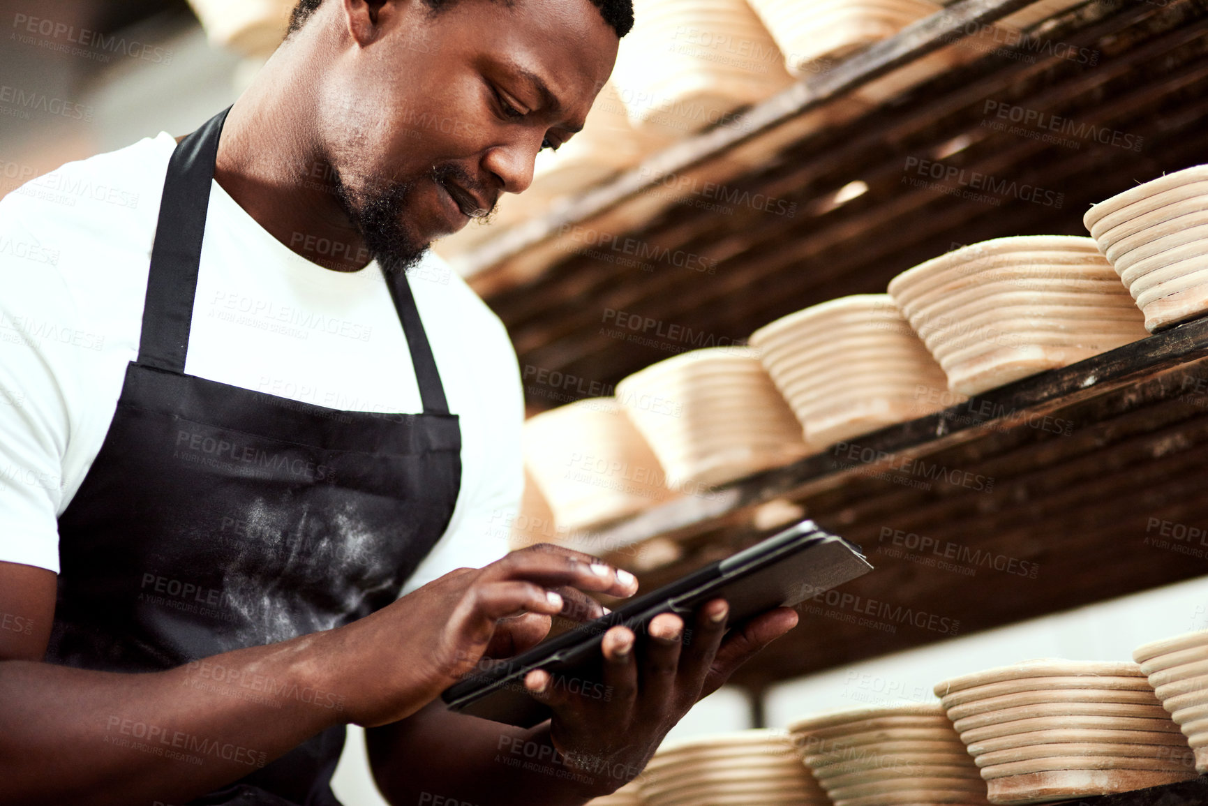Buy stock photo Cropped shot of a man using a digital tablet while working in a bakery