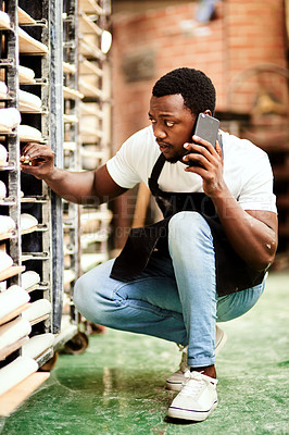 Buy stock photo Shot of a male baker talking on the phone while busy checking a baking trolley