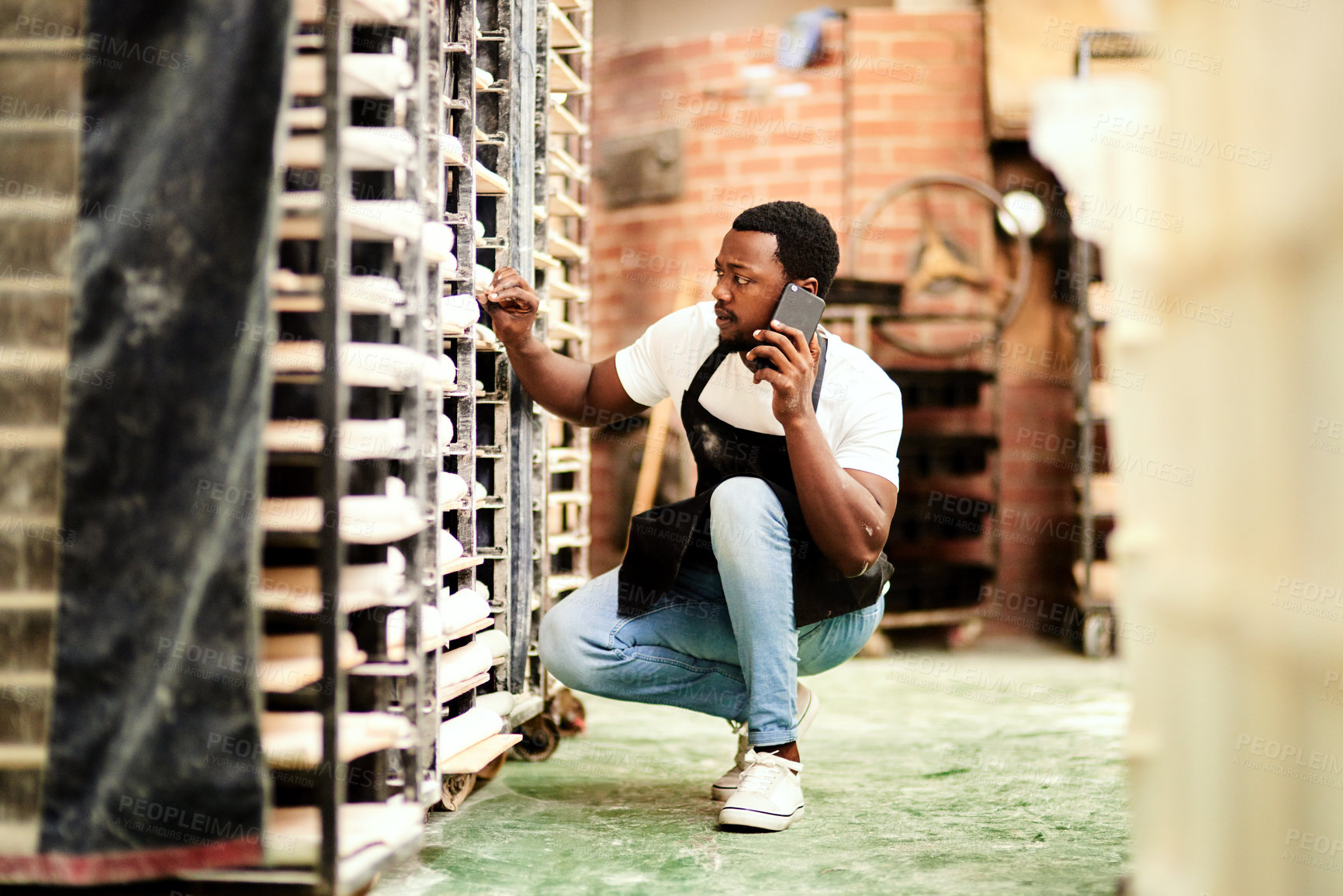 Buy stock photo Black man, bakery or phone call with bread trolley for inventory, pastry production or fresh produce at shop. Young African, male person or baker with mobile smartphone for stock check or management