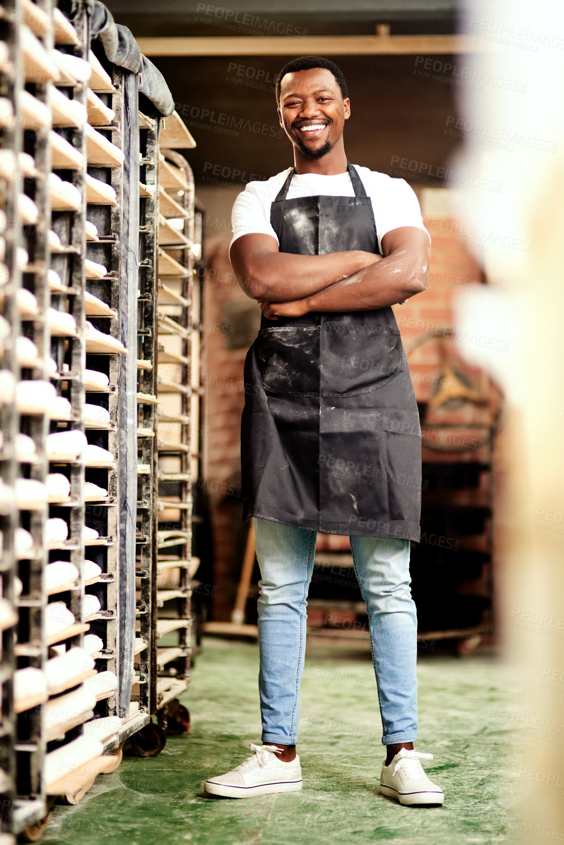 Buy stock photo Shot of a confident young man working in a bakery