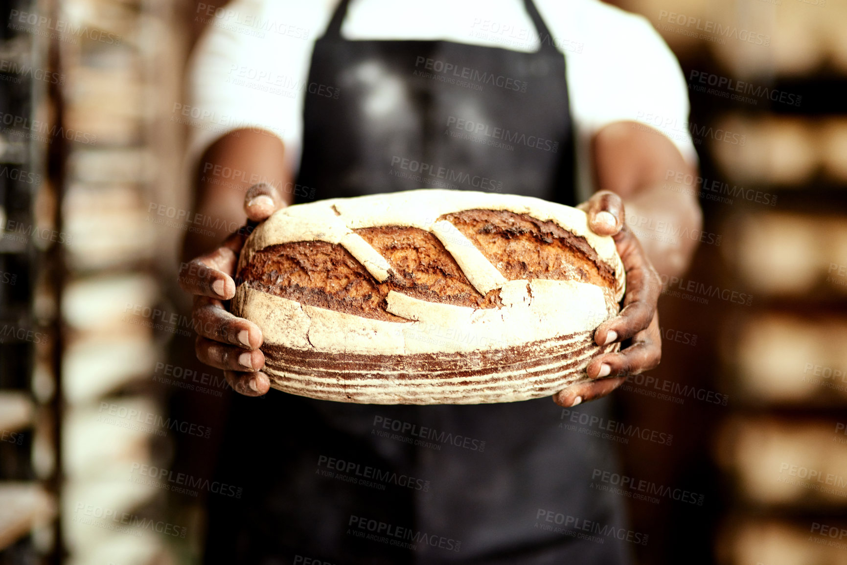 Buy stock photo Cropped shot of a male baker holding a freshly baked loaf of bread in his hands