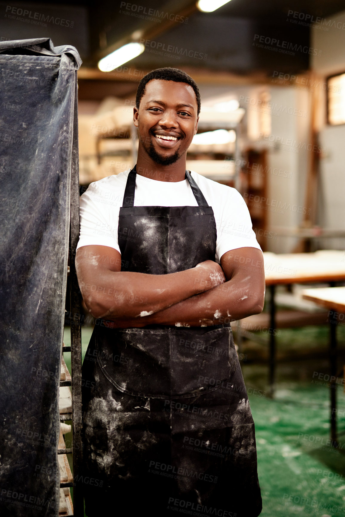 Buy stock photo Shot of a confident young man working in a bakery