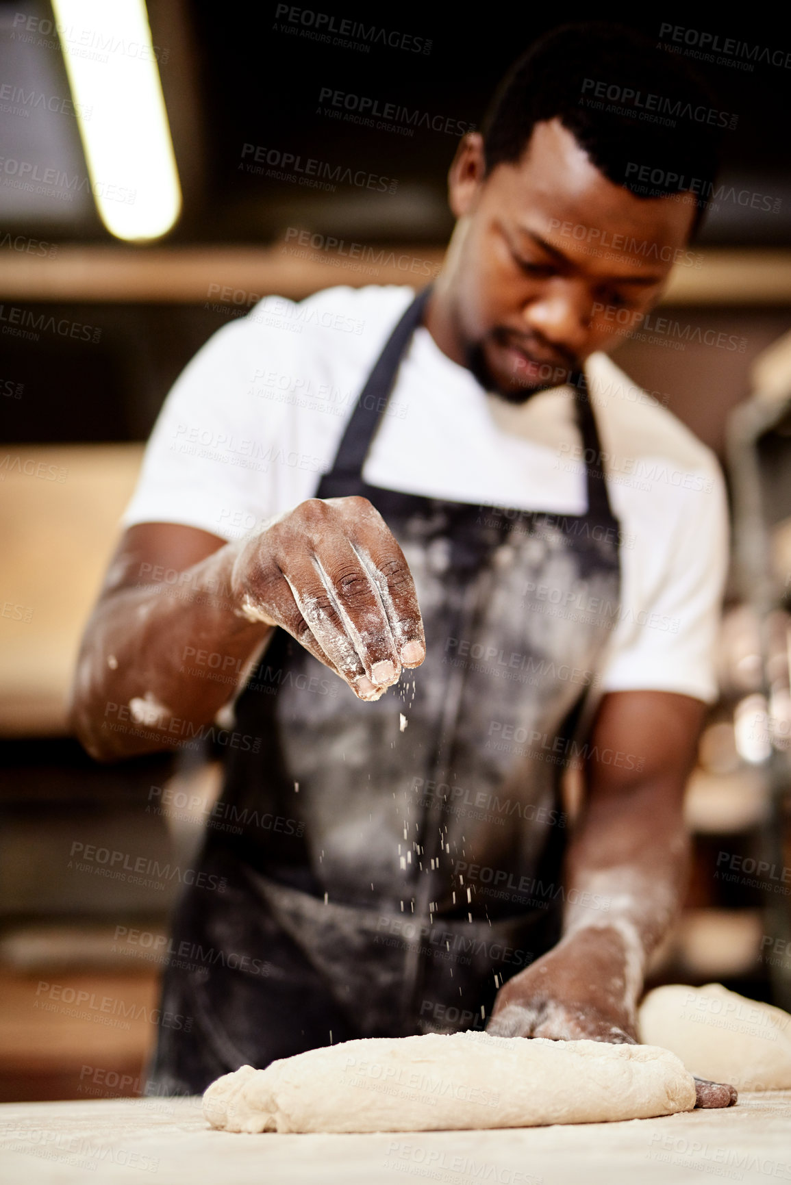 Buy stock photo Cropped shot of a male baker busy shaping dough at work