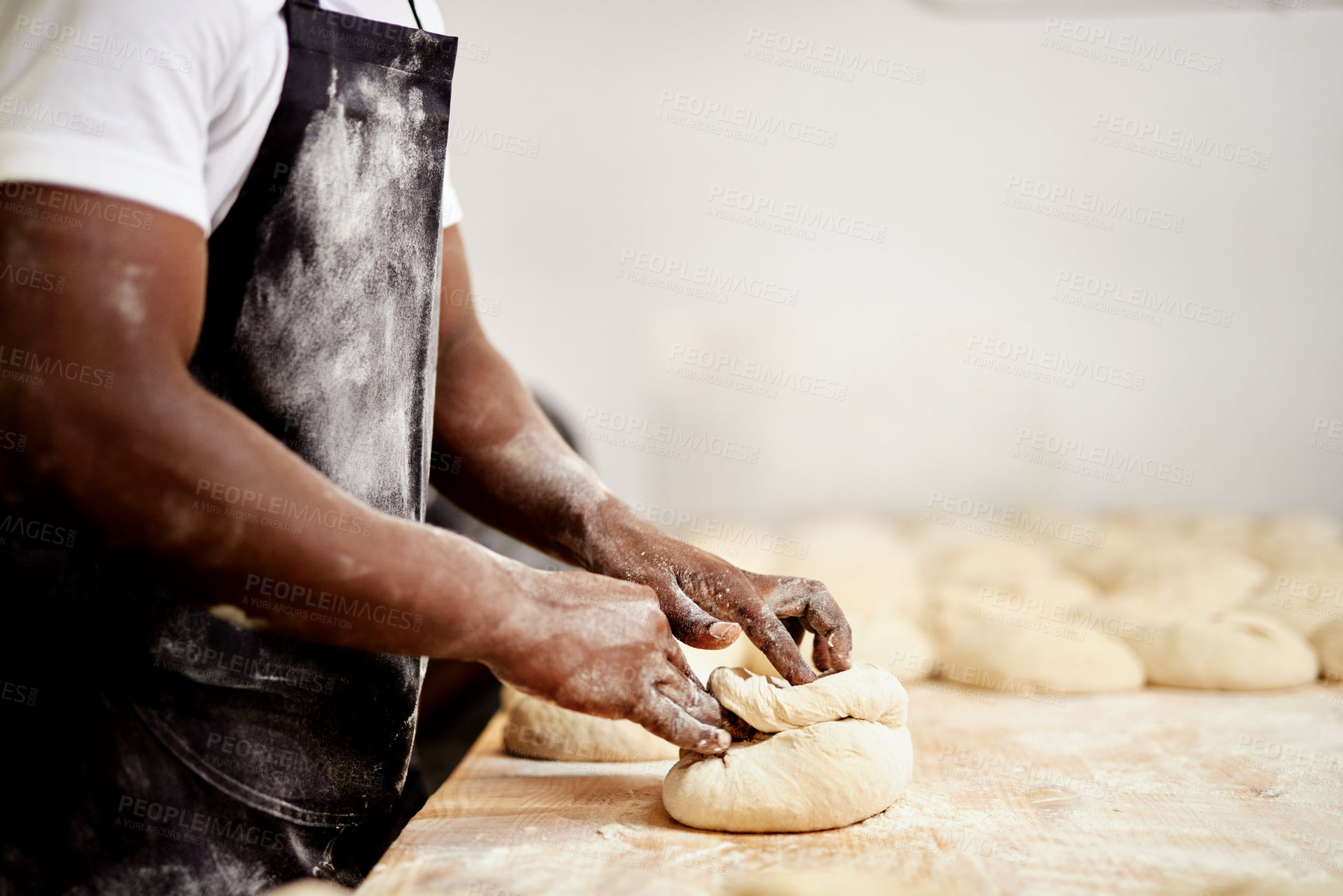 Buy stock photo Cropped shot of a male baker busy shaping dough at work