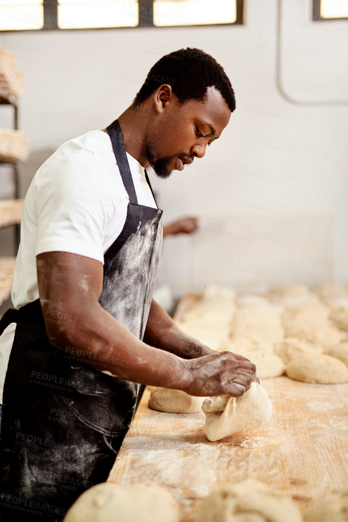 Buy stock photo Cropped shot of a male baker busy shaping dough at work