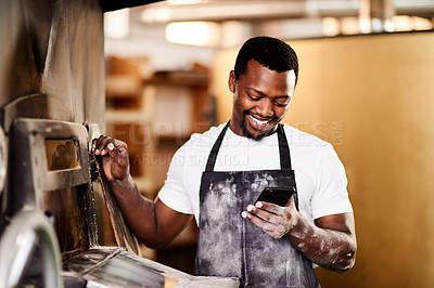 Buy stock photo Cropped shot of a male baker using his cellphone while working