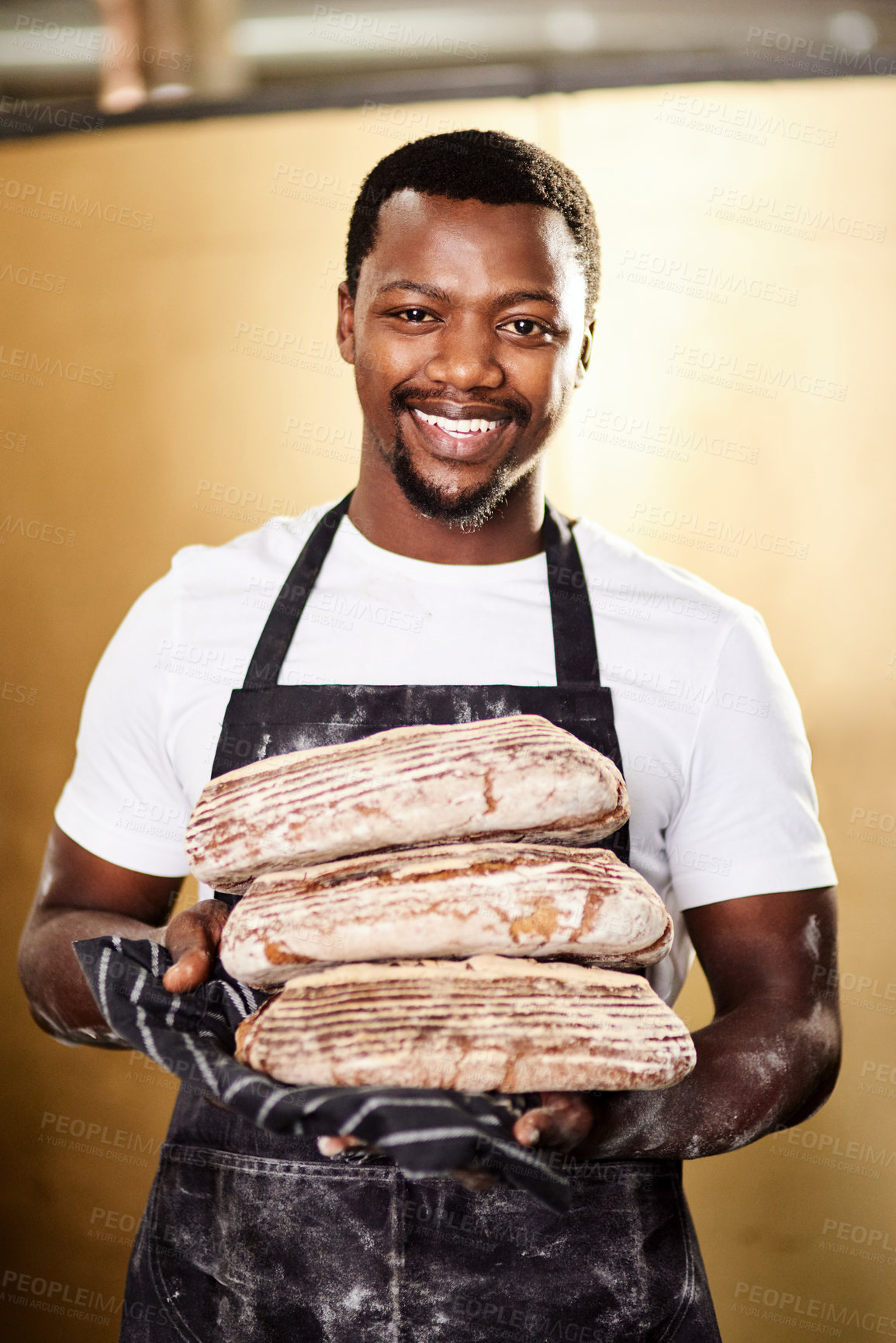 Buy stock photo Cropped shot of a male baker holding up freshly baked bread in his bakery