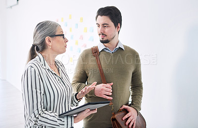 Buy stock photo Shot of two businesspeople using a digital tablet together in an office