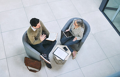 Buy stock photo High angle shot of two businesspeople having a discussion in an office