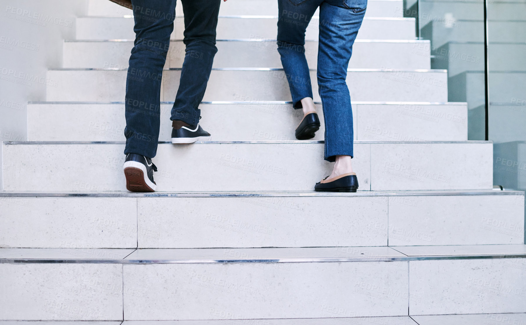 Buy stock photo Rearview shot of two unrecognisable businesspeople walking up a staircase together in an office