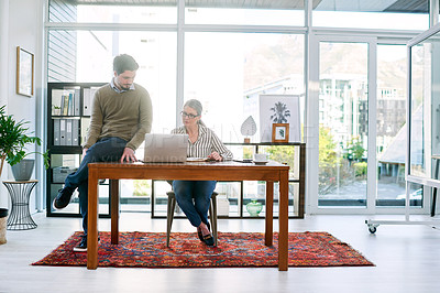 Buy stock photo Shot of two businesspeople working together on a laptop in an office