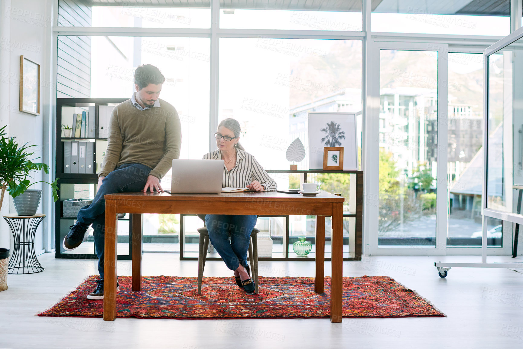 Buy stock photo Shot of two businesspeople working together on a laptop in an office