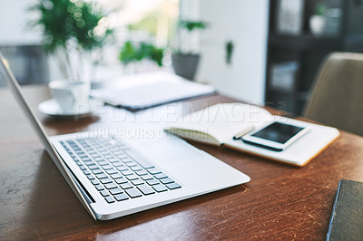 Buy stock photo Still life shot of a laptop, notebook and cellphone on a table in an office