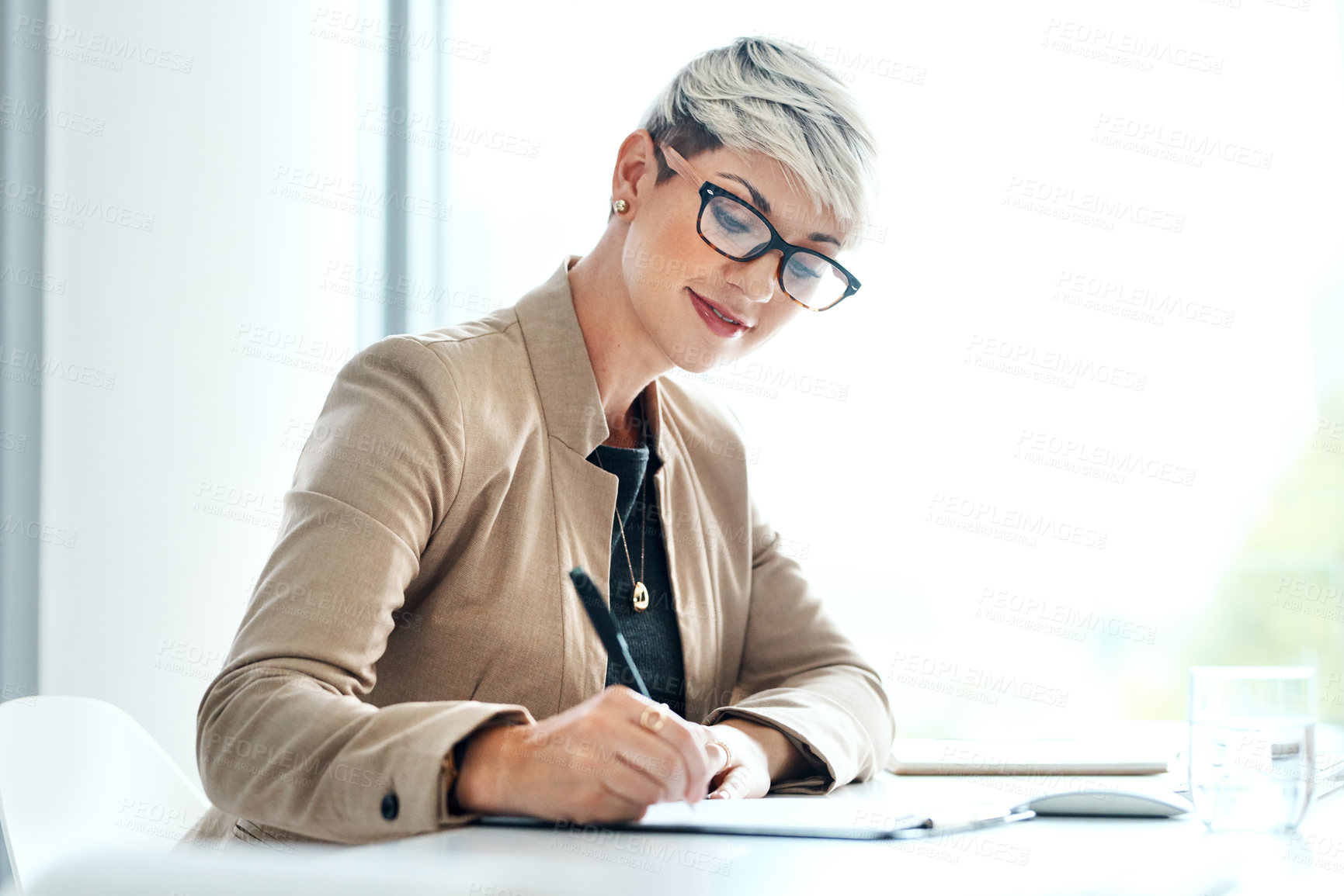 Buy stock photo Shot of a young businesswoman writing notes in an office