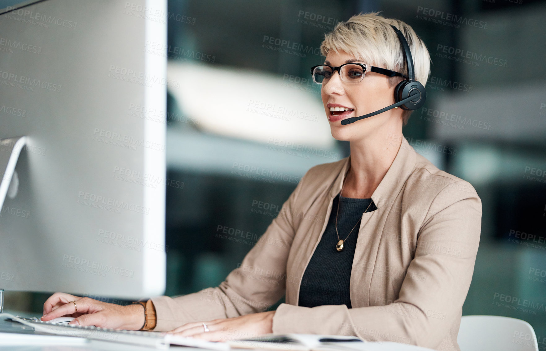 Buy stock photo Shot of a young businesswoman wearing a headset while working on a computer in an office