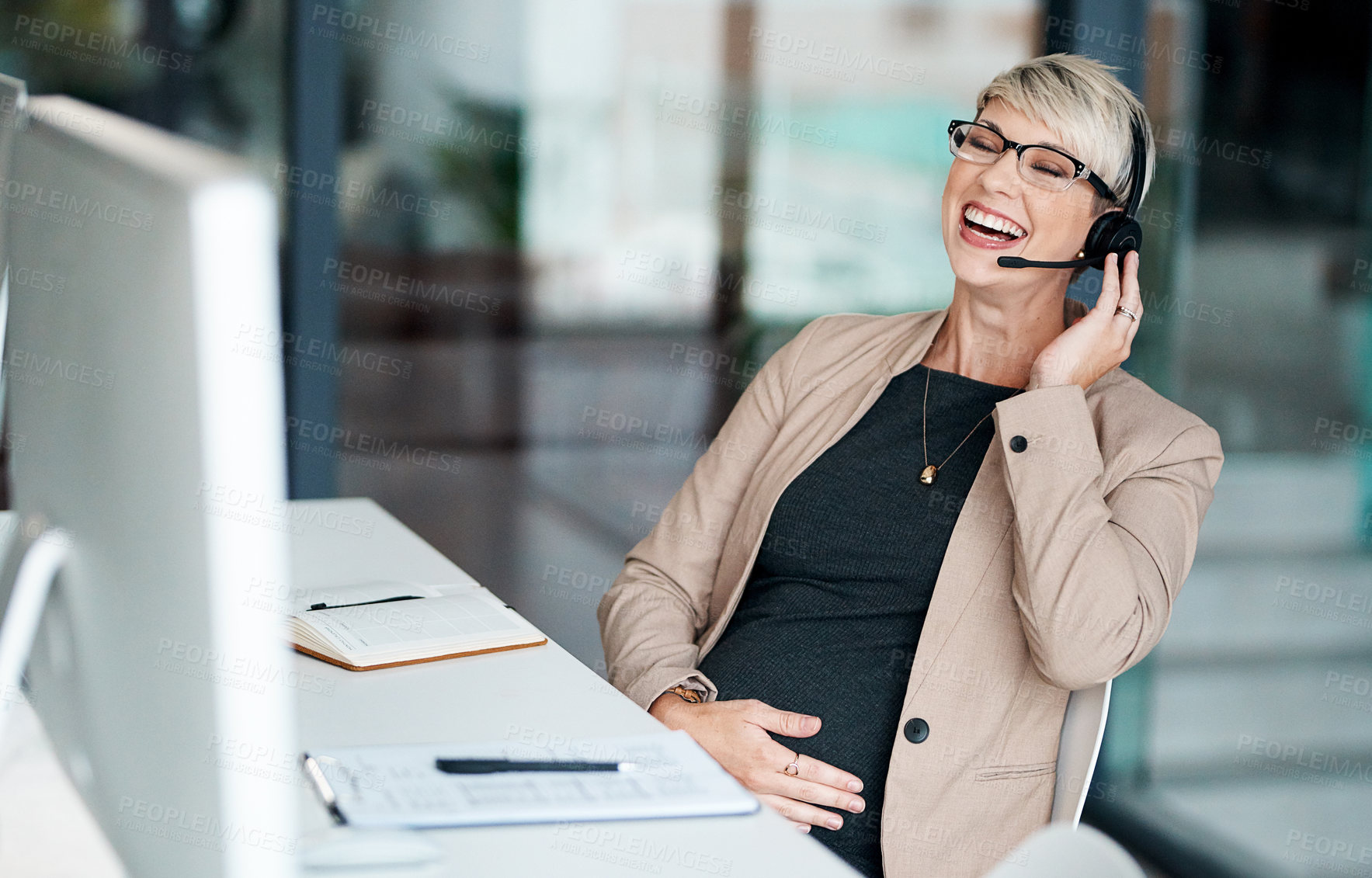 Buy stock photo Shot of a pregnant businesswoman wearing a headset while working in an office
