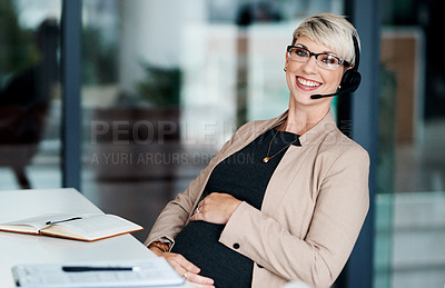 Buy stock photo Portrait of a pregnant businesswoman wearing a headset while working in an office