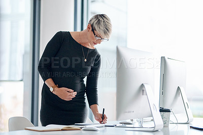 Buy stock photo Shot of a pregnant businesswoman writing notes in an office