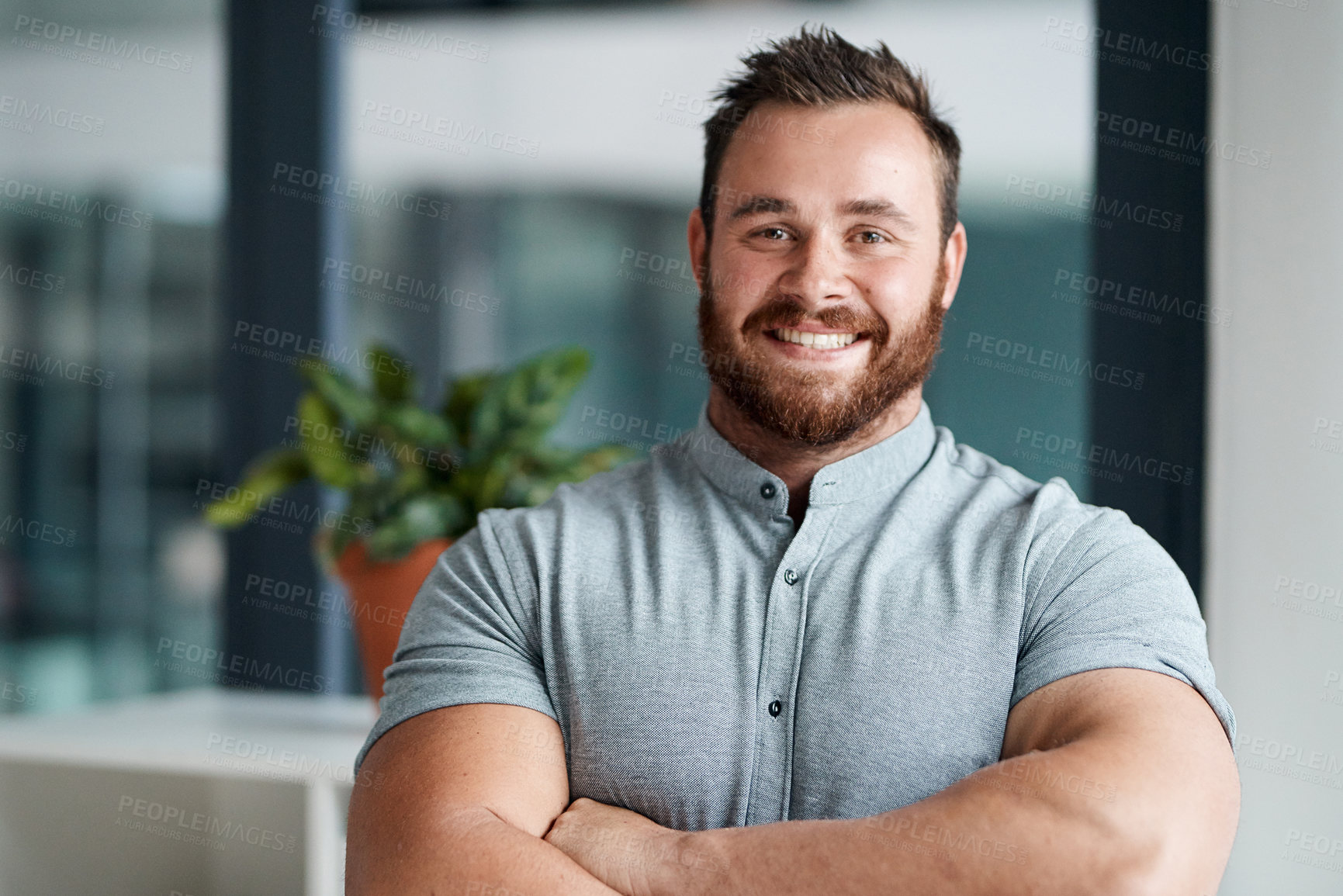 Buy stock photo Portrait of a young businessman standing with his arms crossed in an office