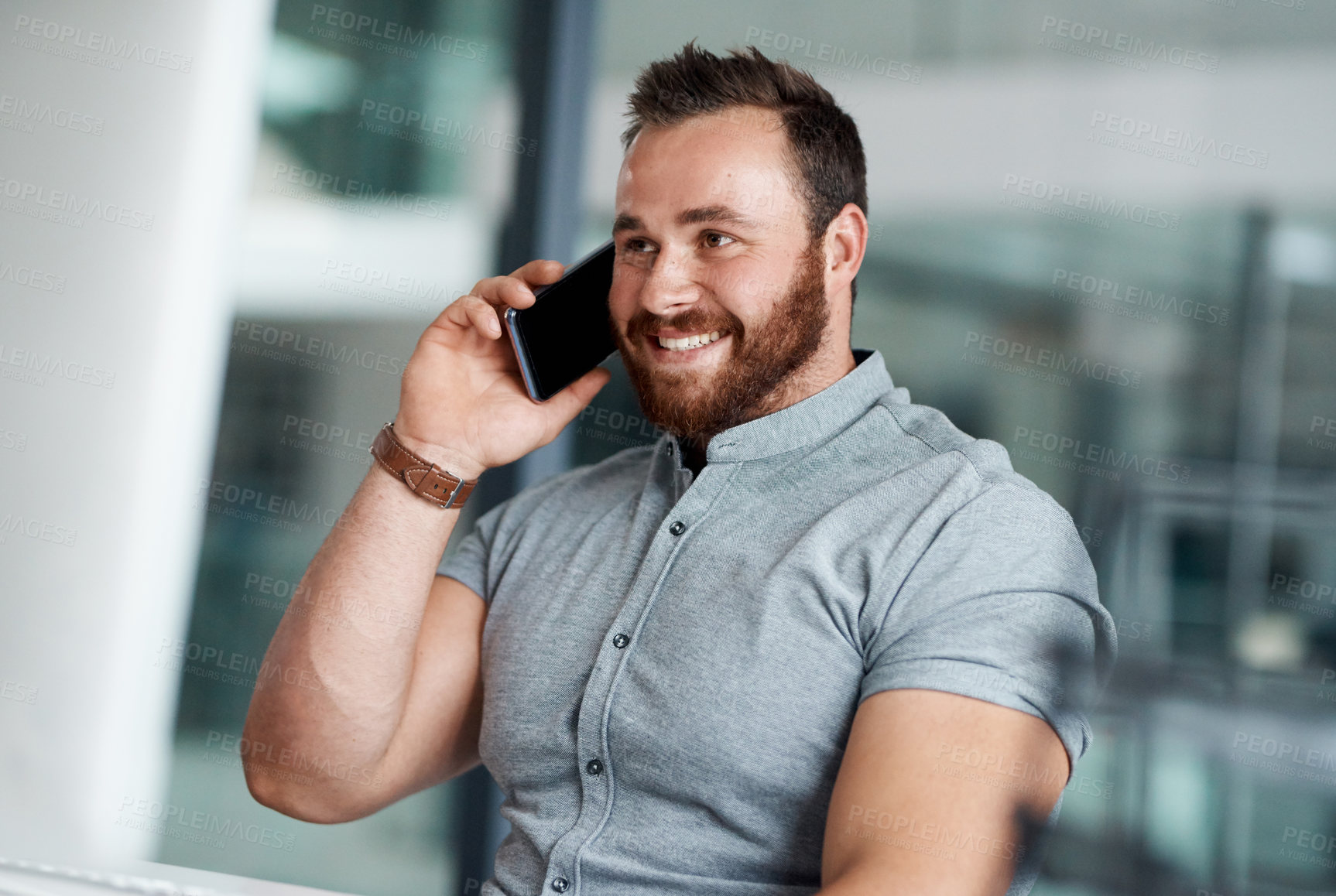 Buy stock photo Shot of a young businessman talking on a cellphone in an office