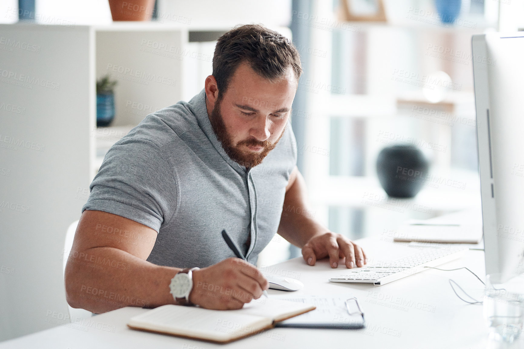 Buy stock photo Shot of a young businessman writing notes in an office