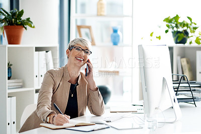 Buy stock photo Shot of a young businesswoman writing notes while talking on a cellphone in an office