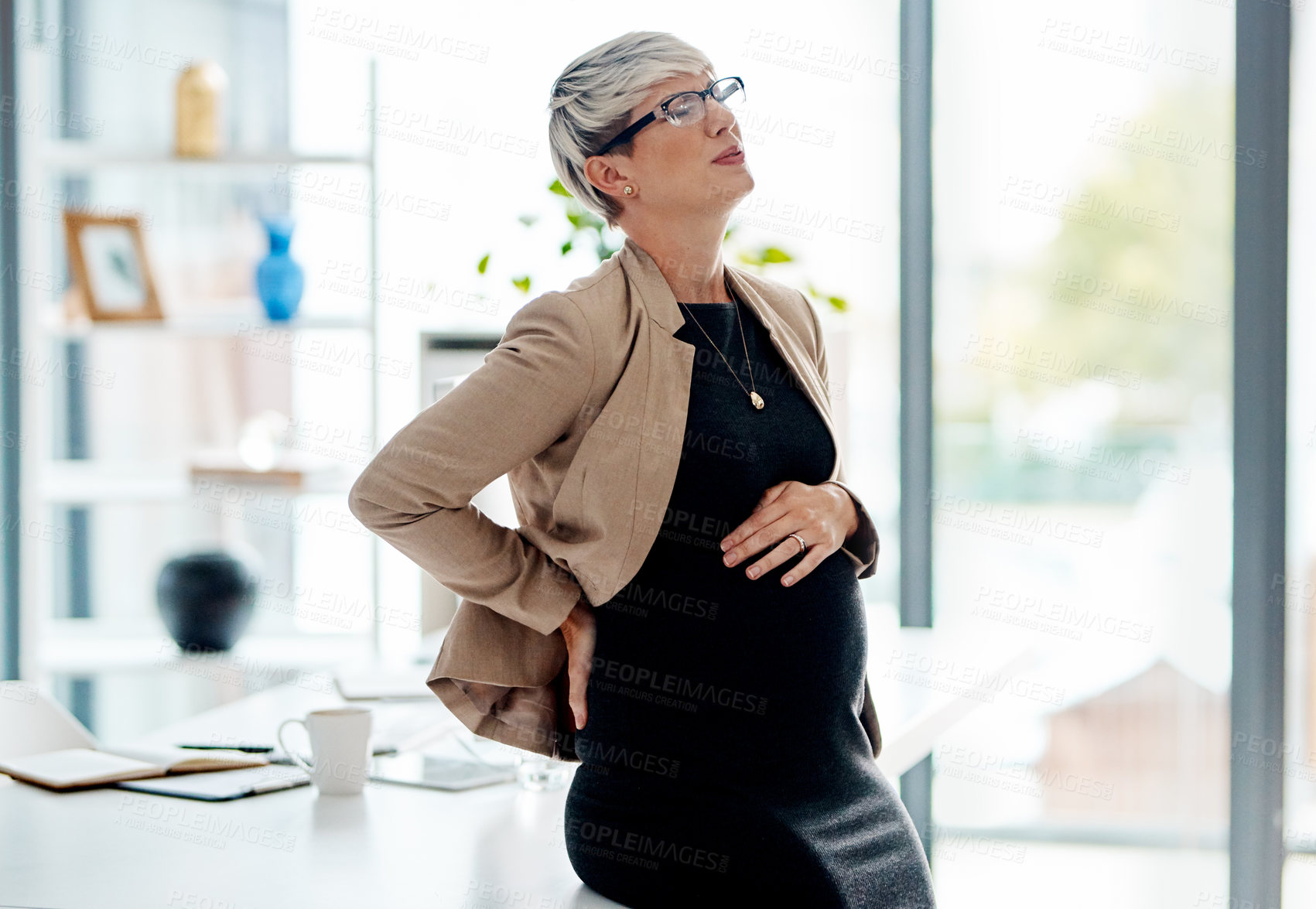 Buy stock photo Shot of a pregnant businesswoman suffering with pain in an office
