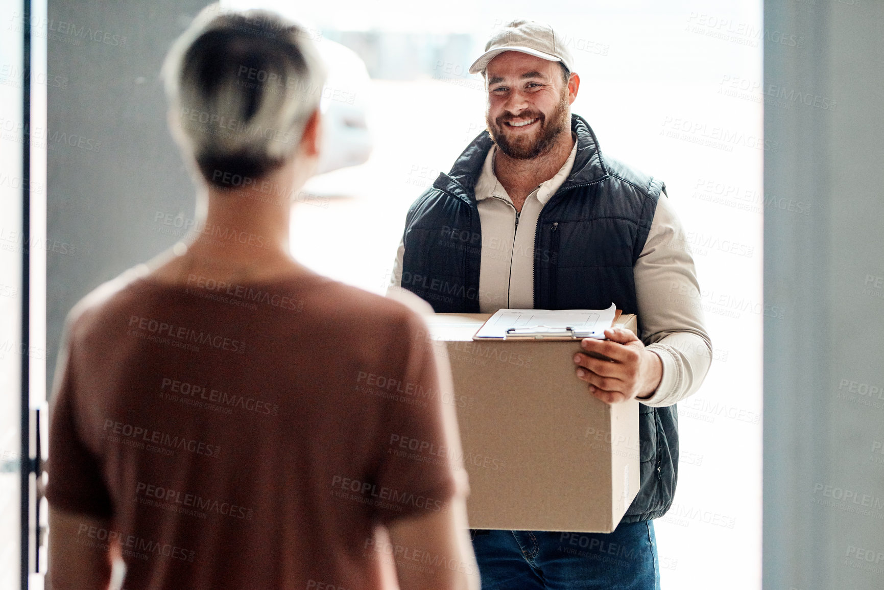 Buy stock photo Shot of a courier making a delivery to a customer at her home