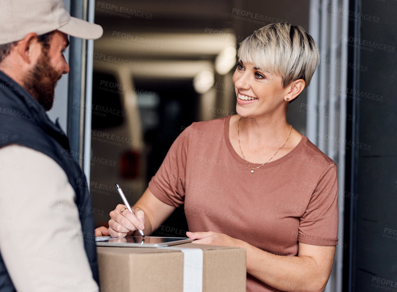 Buy stock photo Shot of a young woman signing for a delivery from the courier