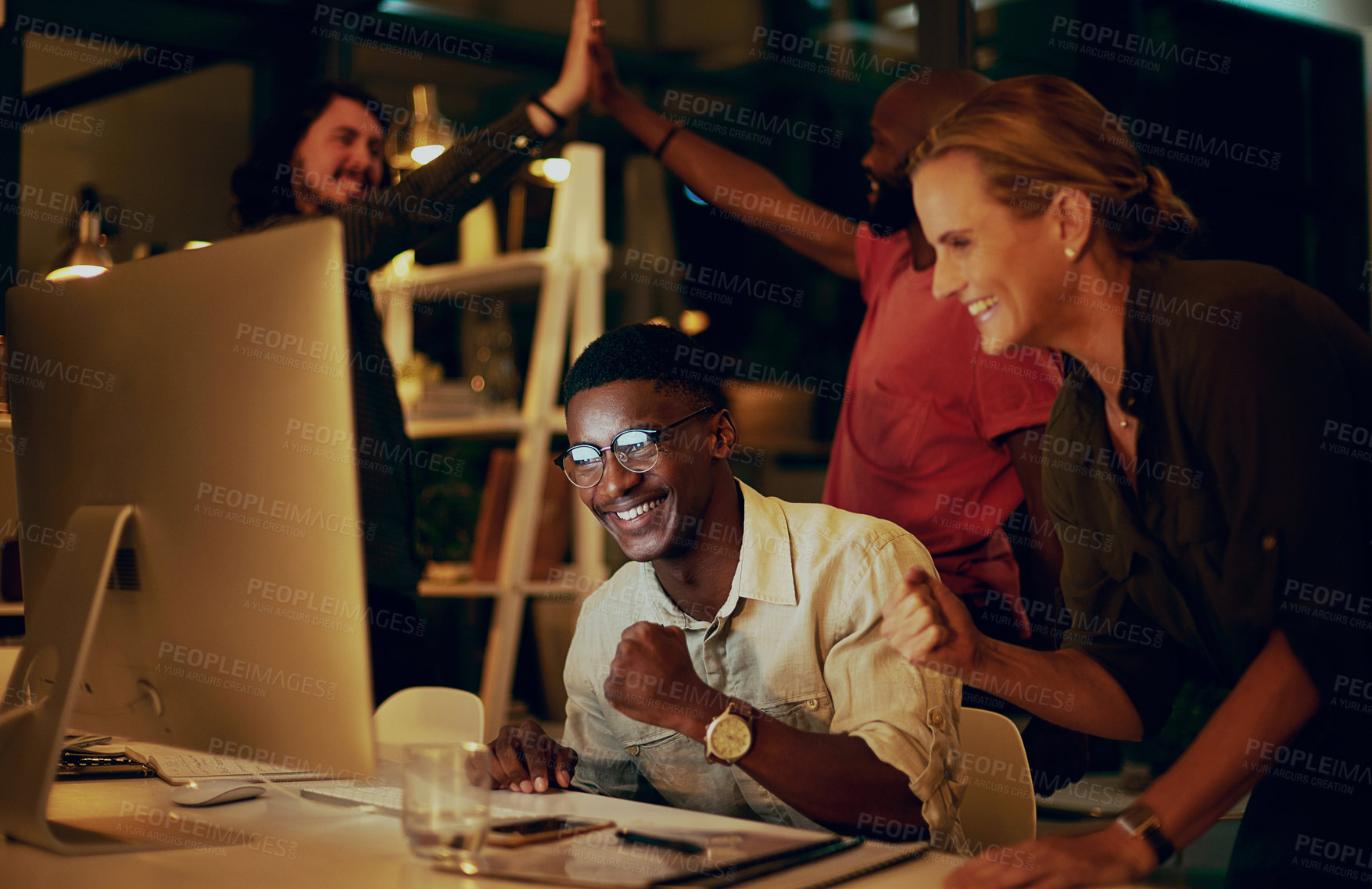 Buy stock photo Shot of a group of businesspeople looking at something on a computer in an office at night