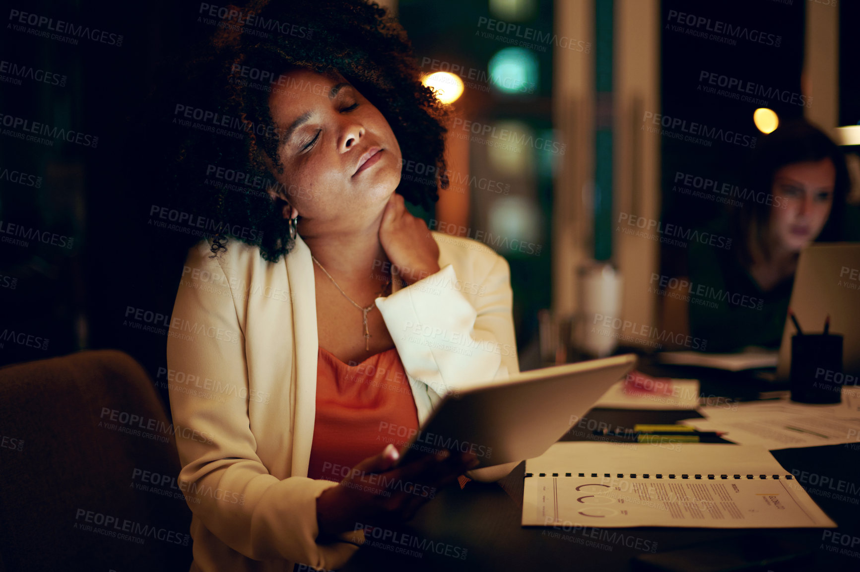 Buy stock photo Shot of a businesswoman experiencing neck pain while using a digital tablet in an office at night