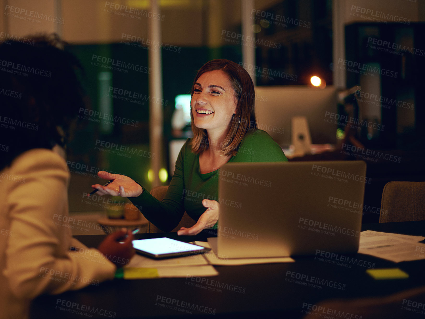 Buy stock photo Shot of two businesswomen working together in an office at night