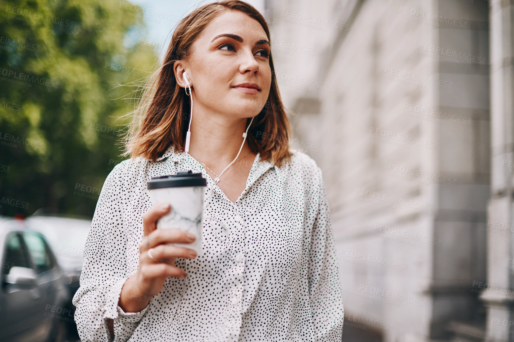 Buy stock photo Shot of a businesswoman holding a coffee and listening to music through earphones while walking through the city