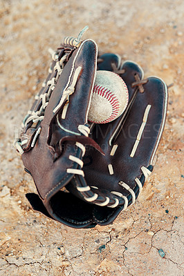 Buy stock photo Shot of a baseball mitt and ball lying on the pitch during the day