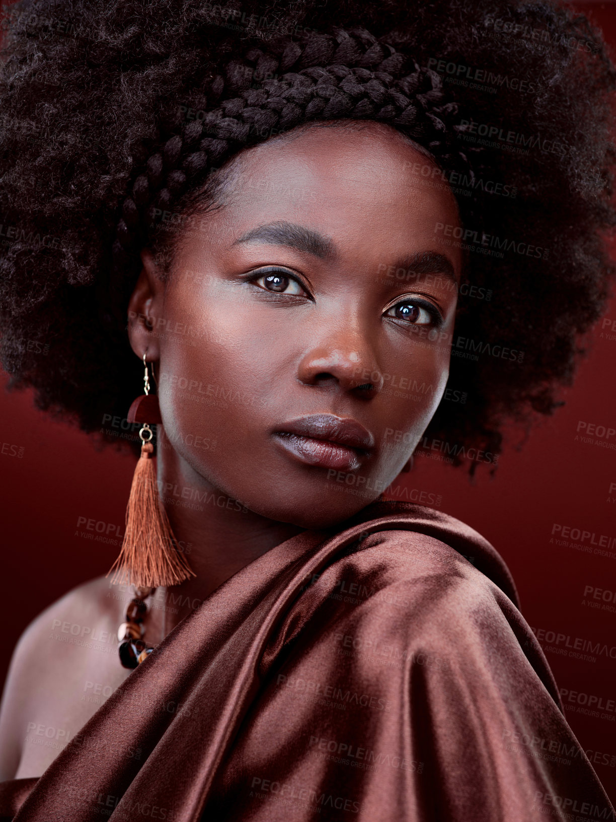 Buy stock photo Natural beauty, face and black woman with fashion in studio isolated on a red background. Portrait, makeup cosmetics and serious African model with stylish outfit, traditional jewelry and aesthetic.
