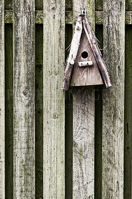 Buy stock photo Old, wooden, and rustic bird feeder hanging on a fence in a backyard garden. Closeup of a vintage birdhouse on a wall outside. Built enclosures for birds in their natural environment and habitat