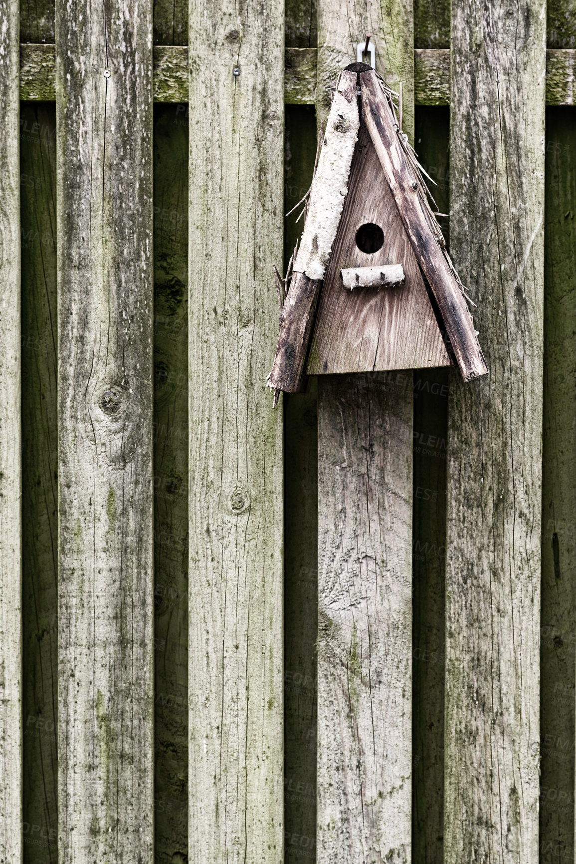 Buy stock photo Old, wooden, and rustic bird feeder hanging on a fence in a backyard garden. Closeup of a vintage birdhouse on a wall outside. Built enclosures for birds in their natural environment and habitat