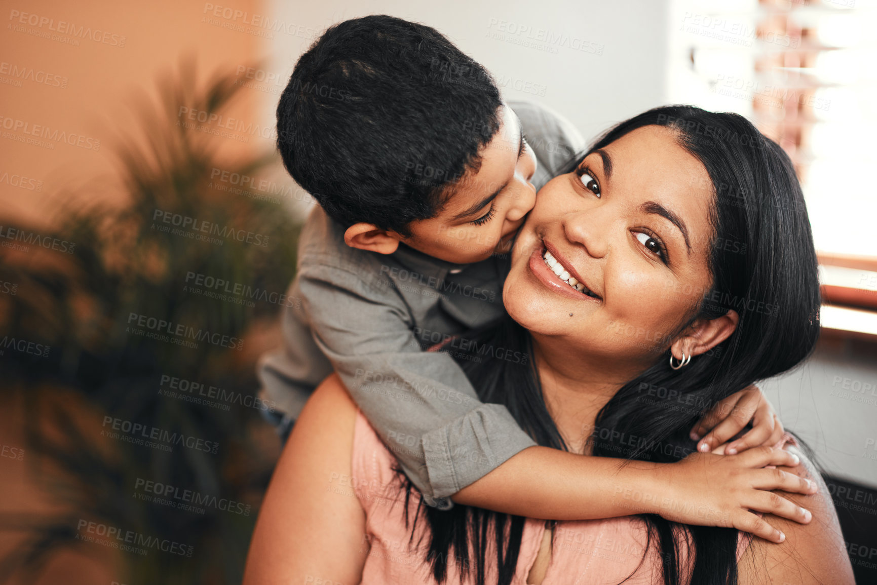 Buy stock photo Shot of an adorable little boy giving his mother a kiss on the cheek at home