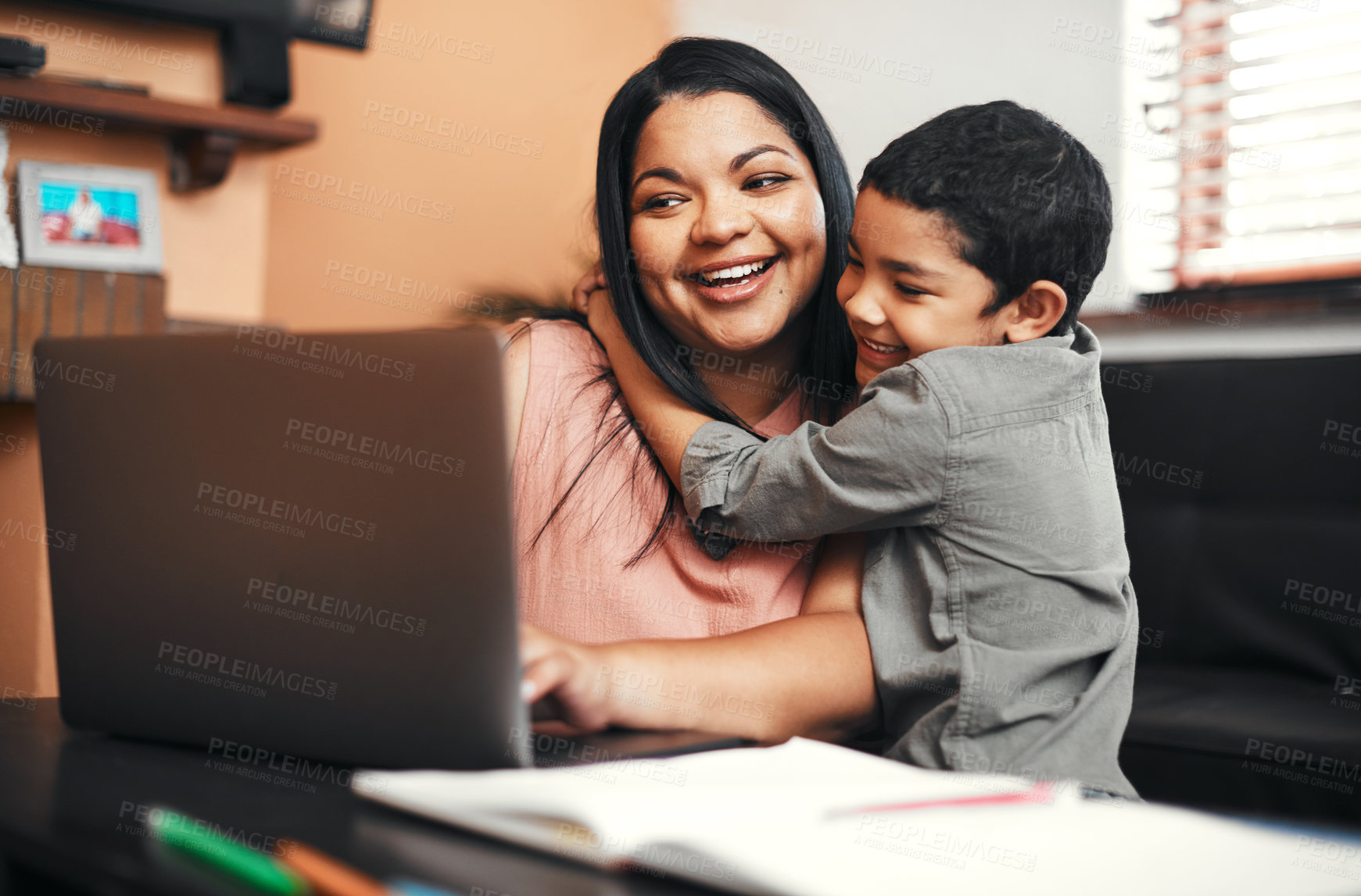 Buy stock photo Shot of a mother using a laptop while her son is hugging her at home