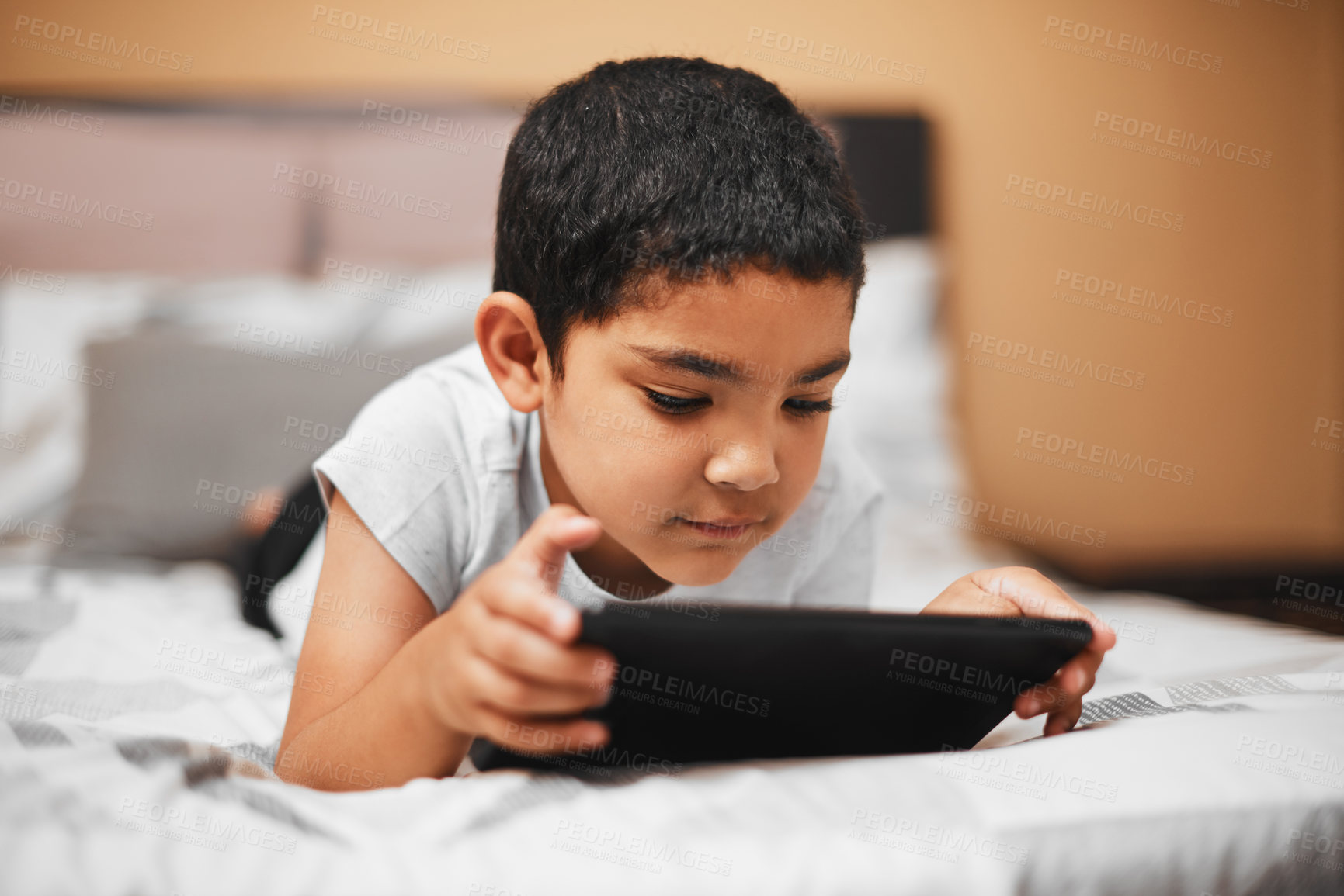 Buy stock photo Shot of an adorable little boy using a digital tablet in a bedroom at home