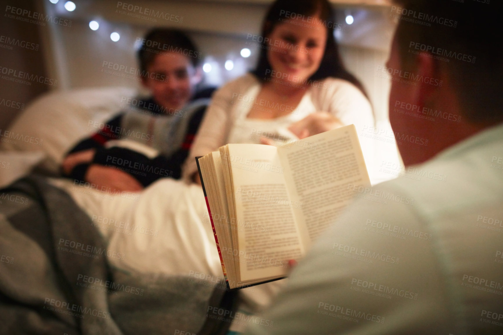 Buy stock photo Cropped shot of a father reading a bedtime story to his wife and son